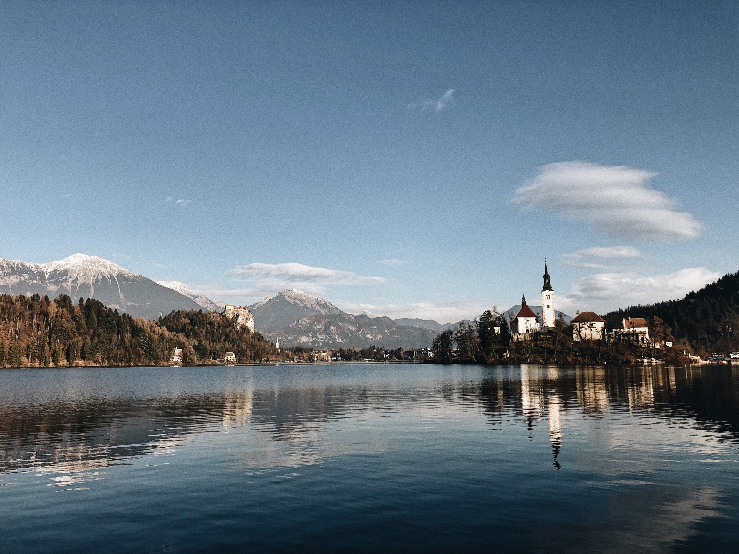 ancient castle surrounded by mountainous scenery reflecting lake